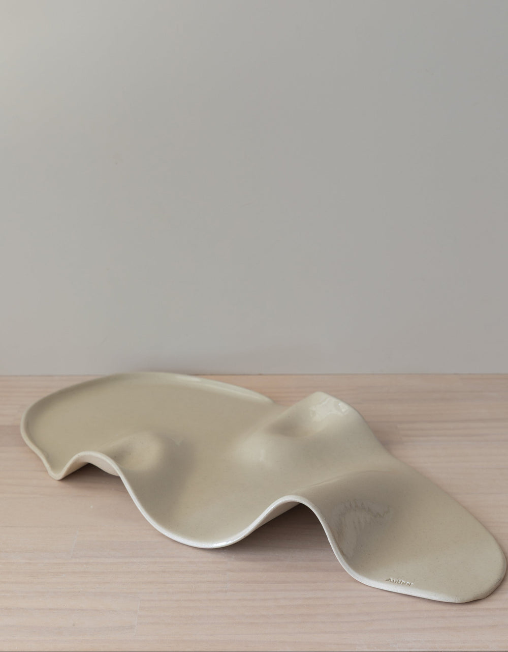 Wavy ceramic plate on a wooden surface with a plain background