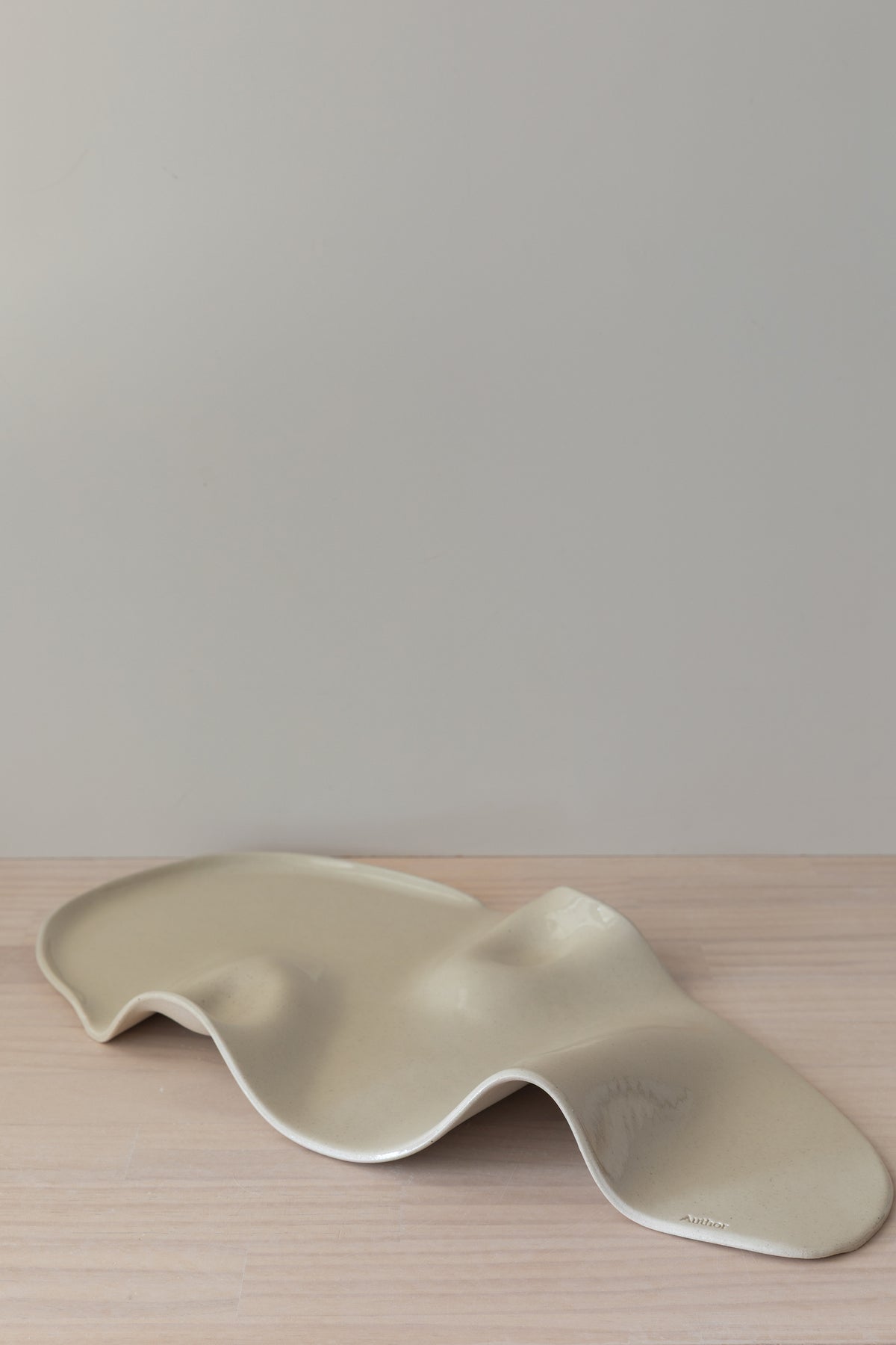 Wavy ceramic plate on a wooden surface with a plain background